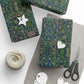 Gifts wrapped in green and blue patterned paper with decorative tags and scissors on a white surface.