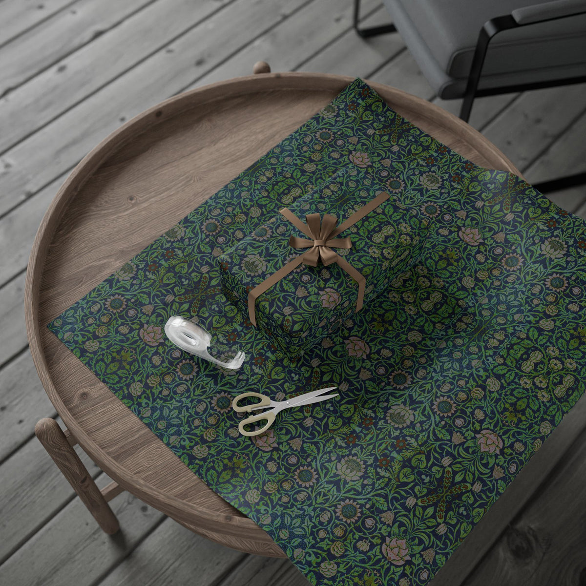 Green floral-patterned wrapping paper on a wooden tray with scissors and a spool of thread.