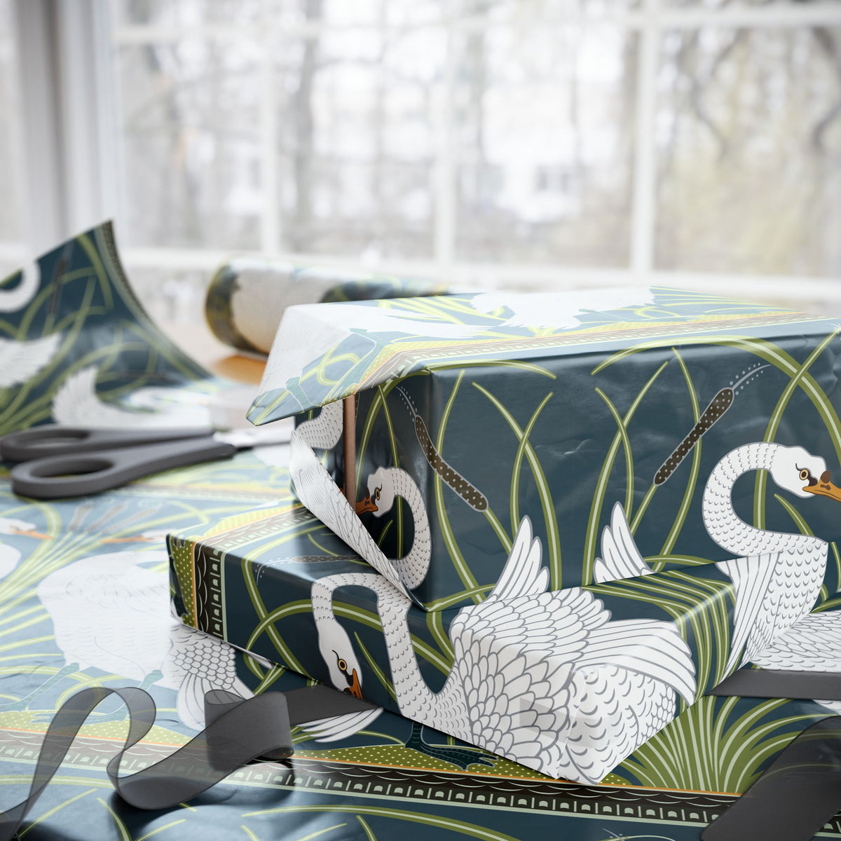Gift box with swan design wrapping paper on a table with scissors.