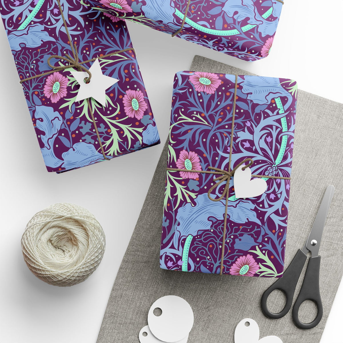 Gift-wrapped items with floral pattern, scissors, and yarn on a white surface