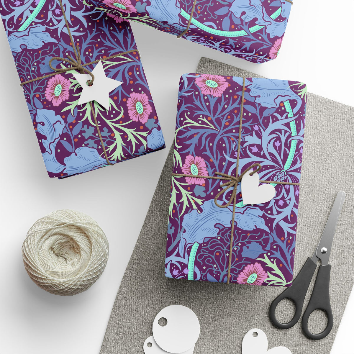 Gift-wrapped items with floral pattern, scissors, and yarn on a white surface