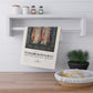 Decorative towel with William Morris & Co design hanging on a wall shelf above a wooden surface.