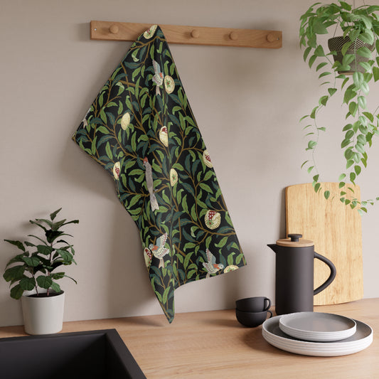 A kitchen tea towel with a design inspired by William Morris, featuring birds and pomegranate patterns on a dark background.