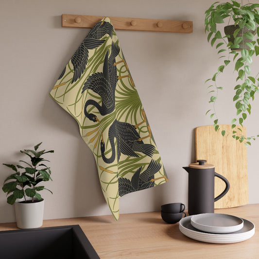 A kitchen tea towel with a repeating William Morris & Co pattern of black swans and green foliage on a beige background.