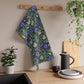 A kitchen tea towel with a floral William Morris & Co pattern featuring blue and green colours on a beige background.