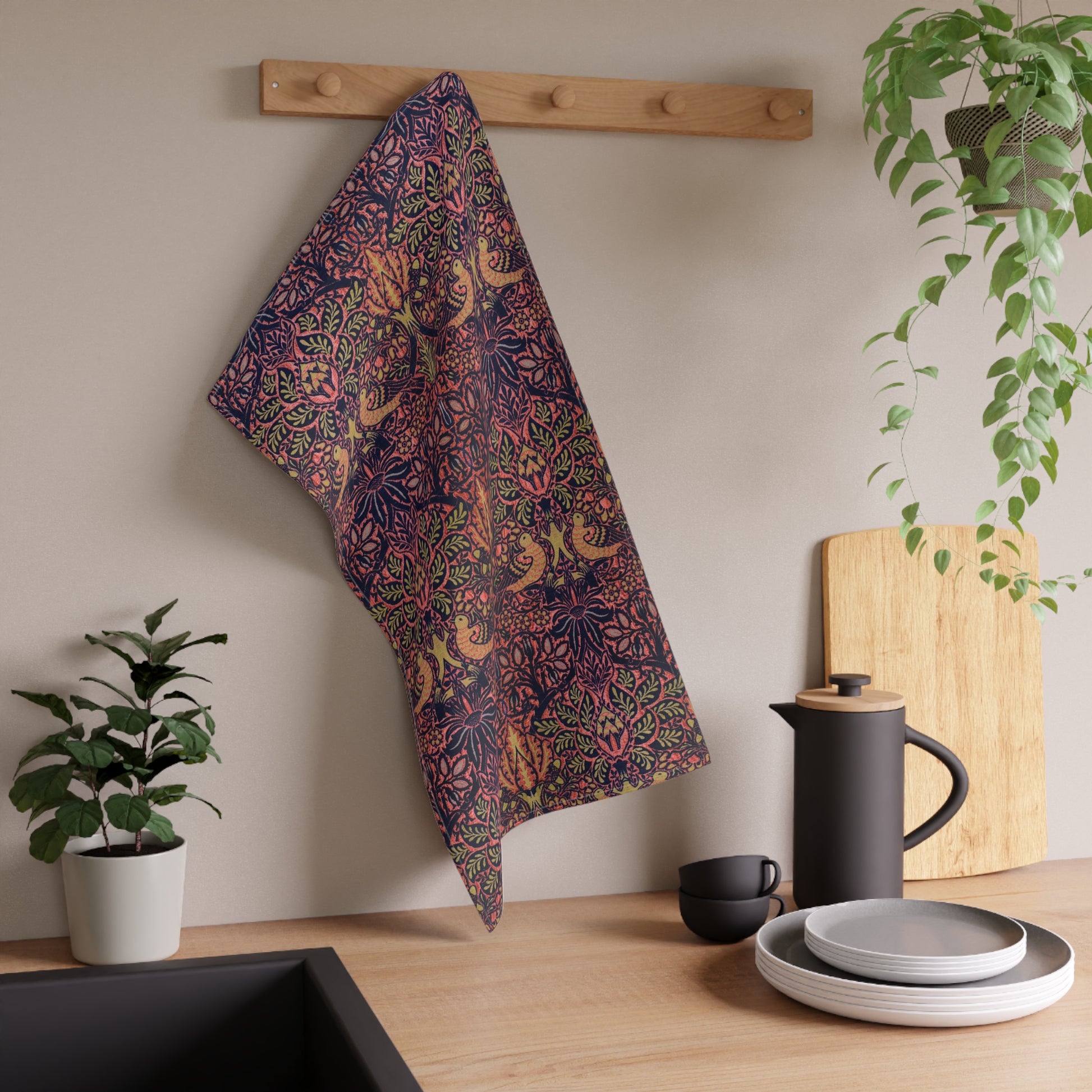 A kitchen tea towel with a floral and geometric pattern, predominantly in pink and purple colours.