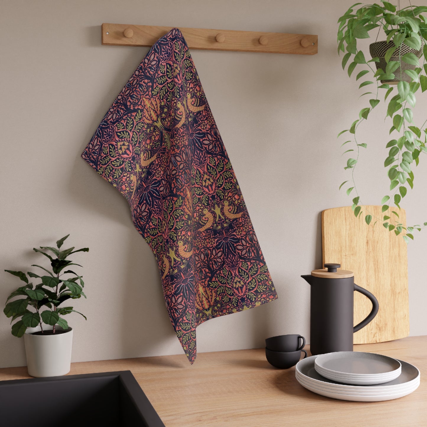 A kitchen tea towel with a floral and geometric pattern, predominantly in pink and purple colours.