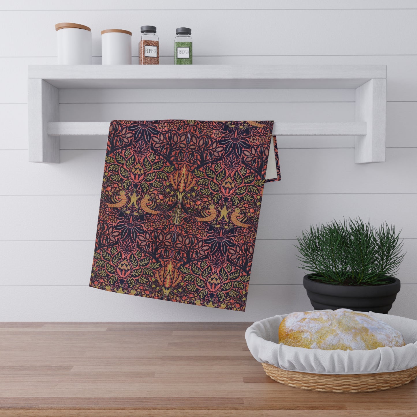 A kitchen tea towel with a floral and geometric pattern, predominantly in pink and purple colours.