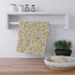 Floral patterned towel hanging on a rack with a basket and plant in the foreground.