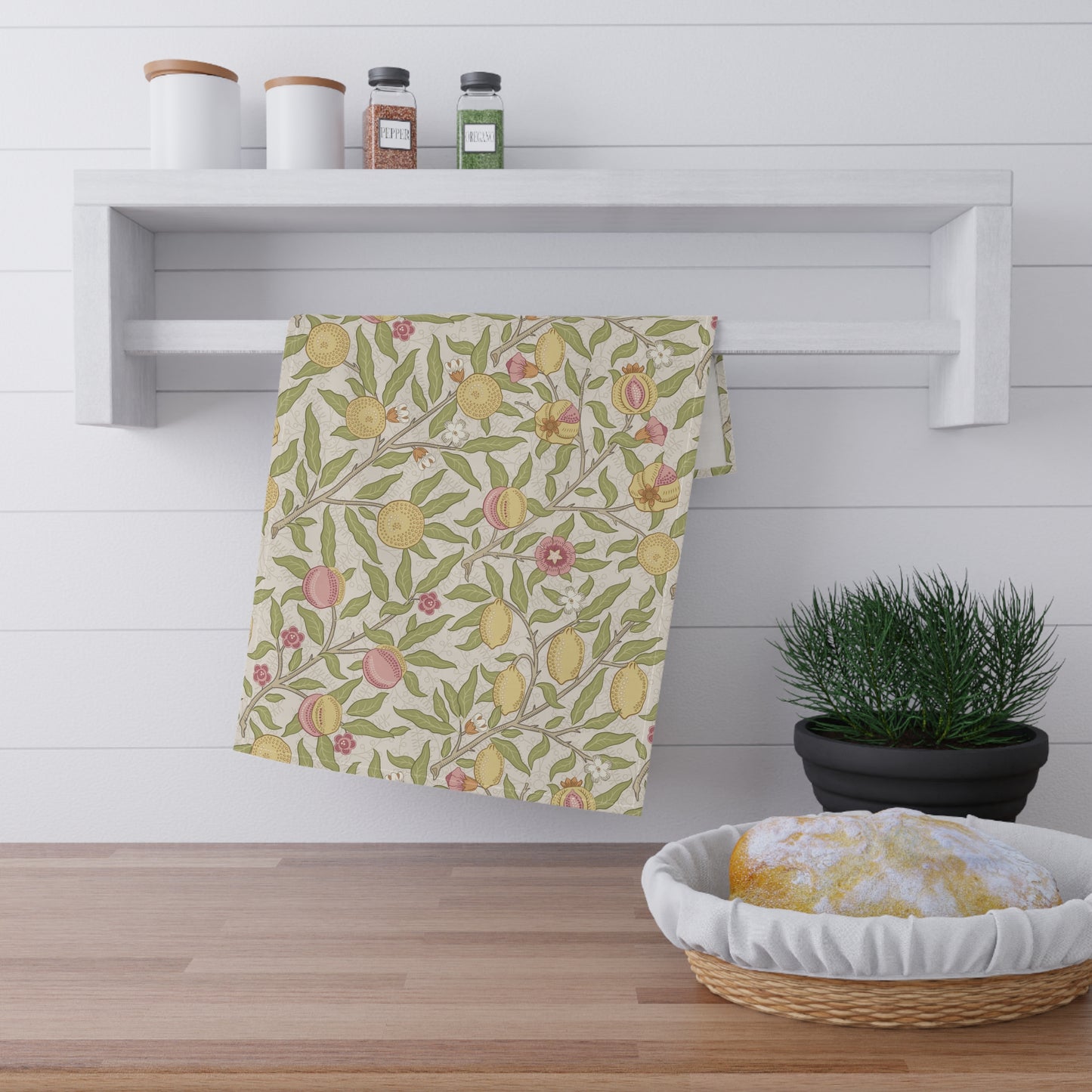 Floral patterned towel hanging on a rack with a basket and plant in the foreground.