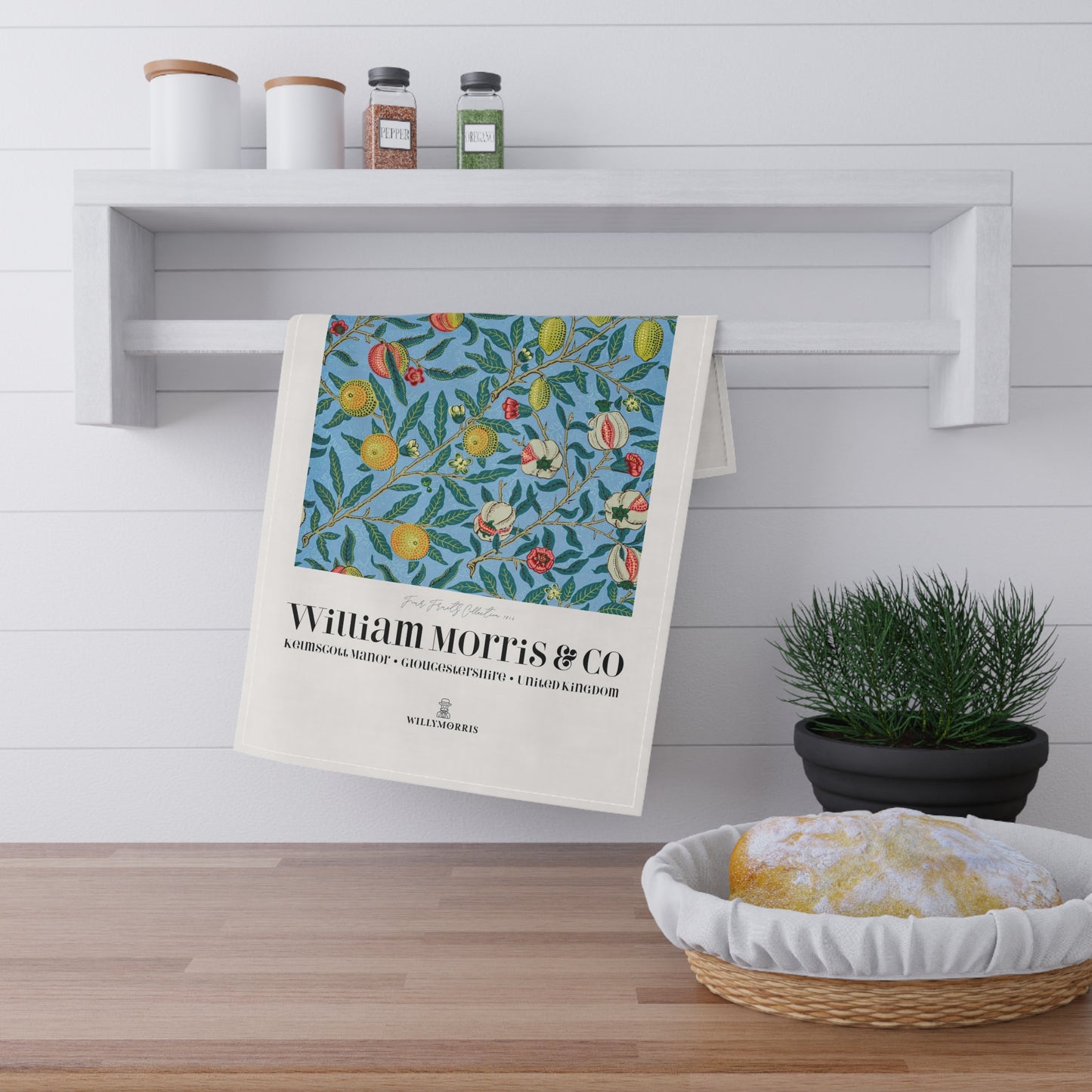 Decorative towel with floral pattern and 'William Morris & Co' branding hanging on a shelf.