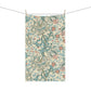 A rectangular tea towel with an ornate floral pattern, suspended by clips from a string against a plain white background.