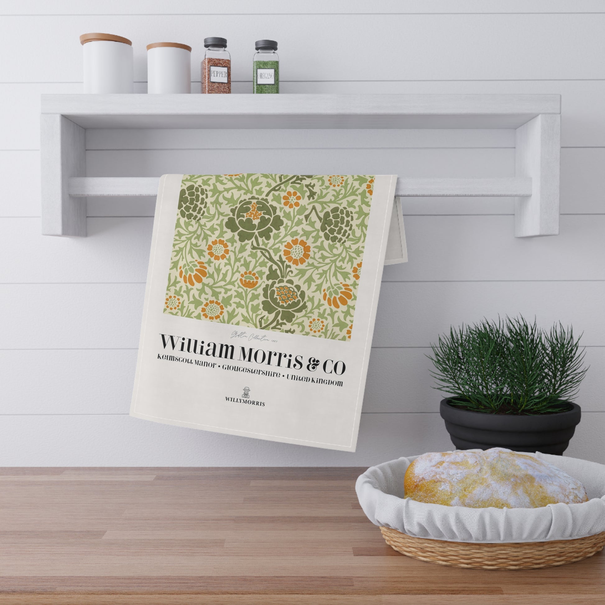 Decorative towel with floral pattern and 'William Morris & Co' text hanging on a shelf in a kitchen.