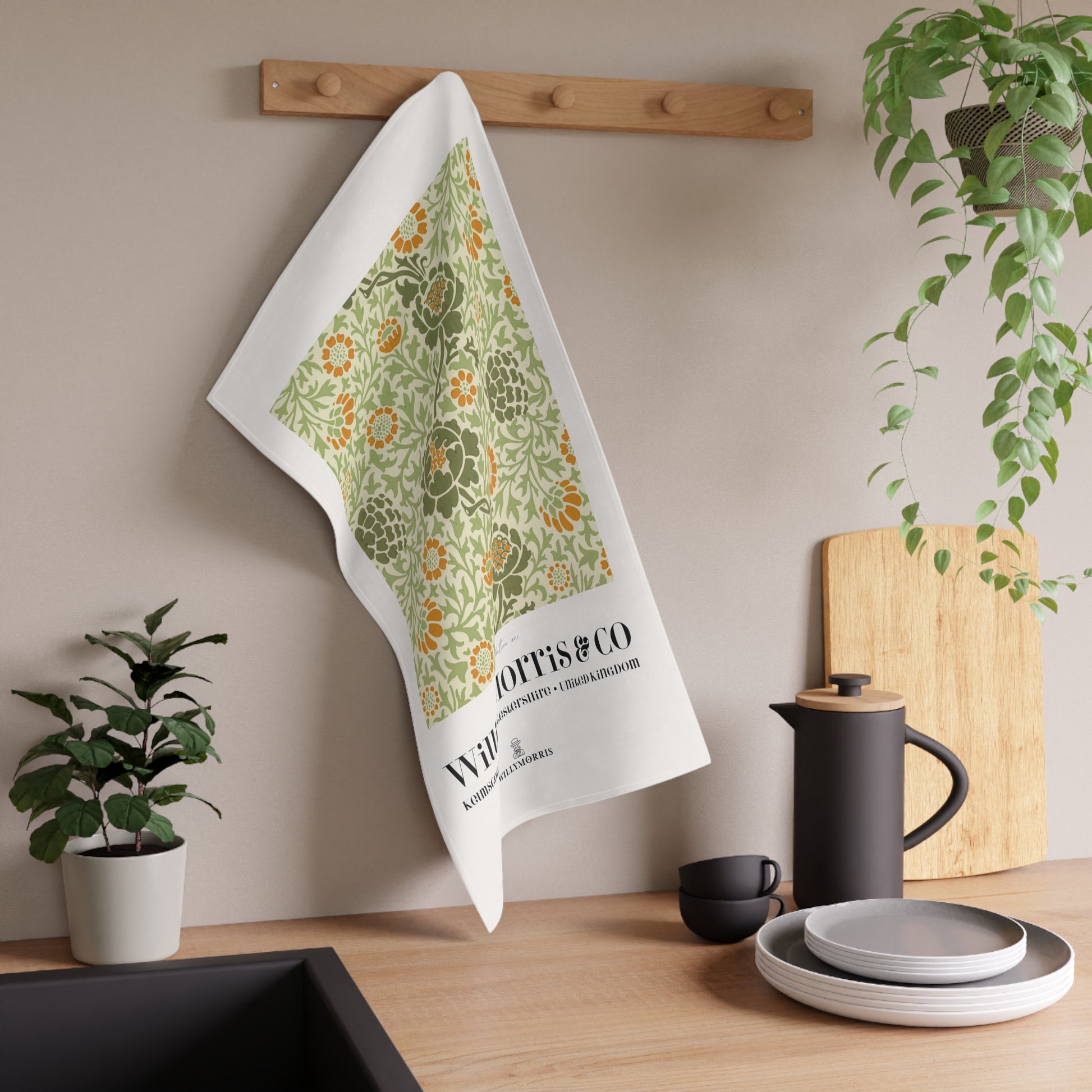 Floral towel hanging on a wooden rack with kitchen items and plants in the background