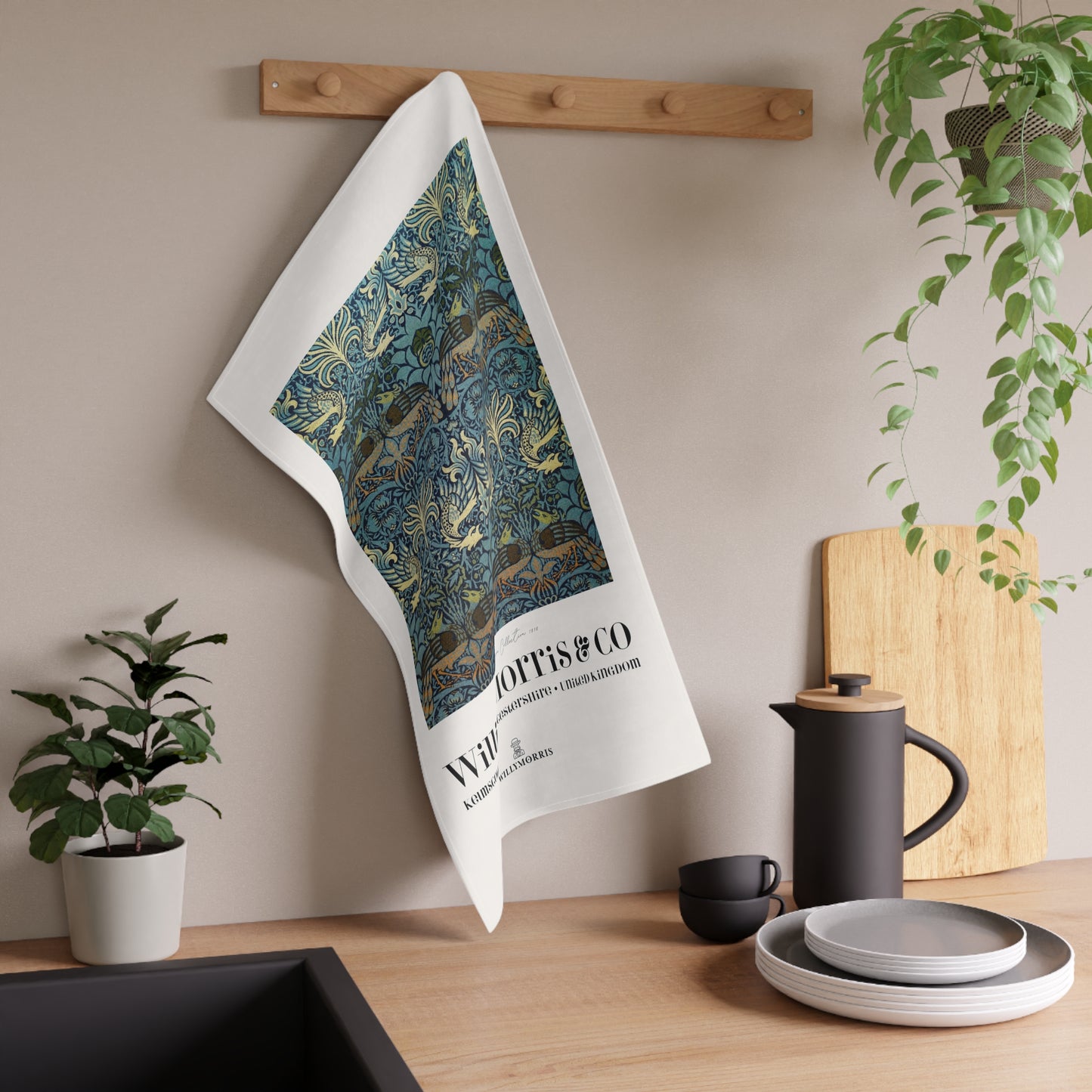 Tea towel with decorative design hanging on a wooden rack in a kitchen setting.