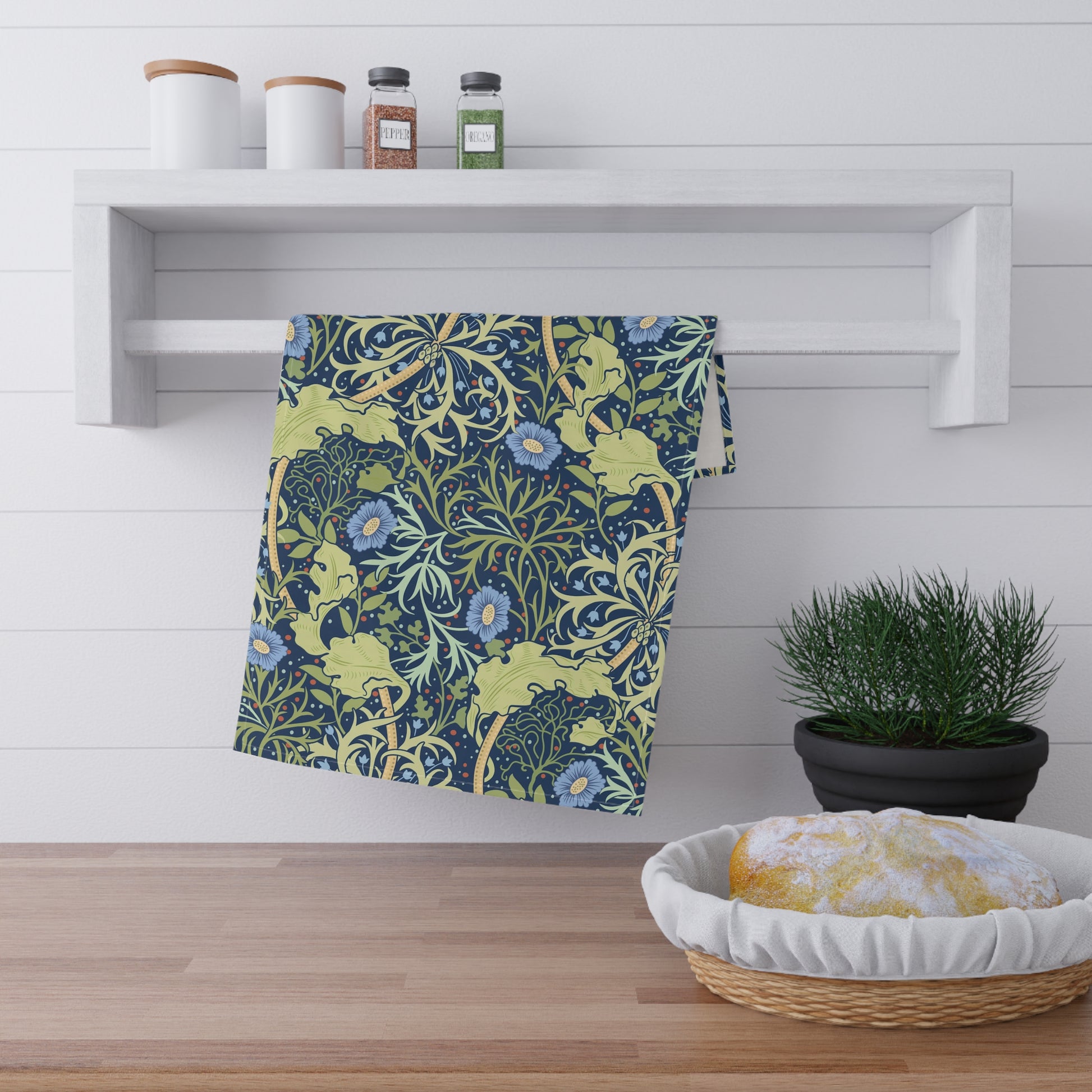 A rectangular kitchen tea towel featuring a floral Arts & Crafts pattern from William Morris & Co with blue flowers and green leaves on a cream background.