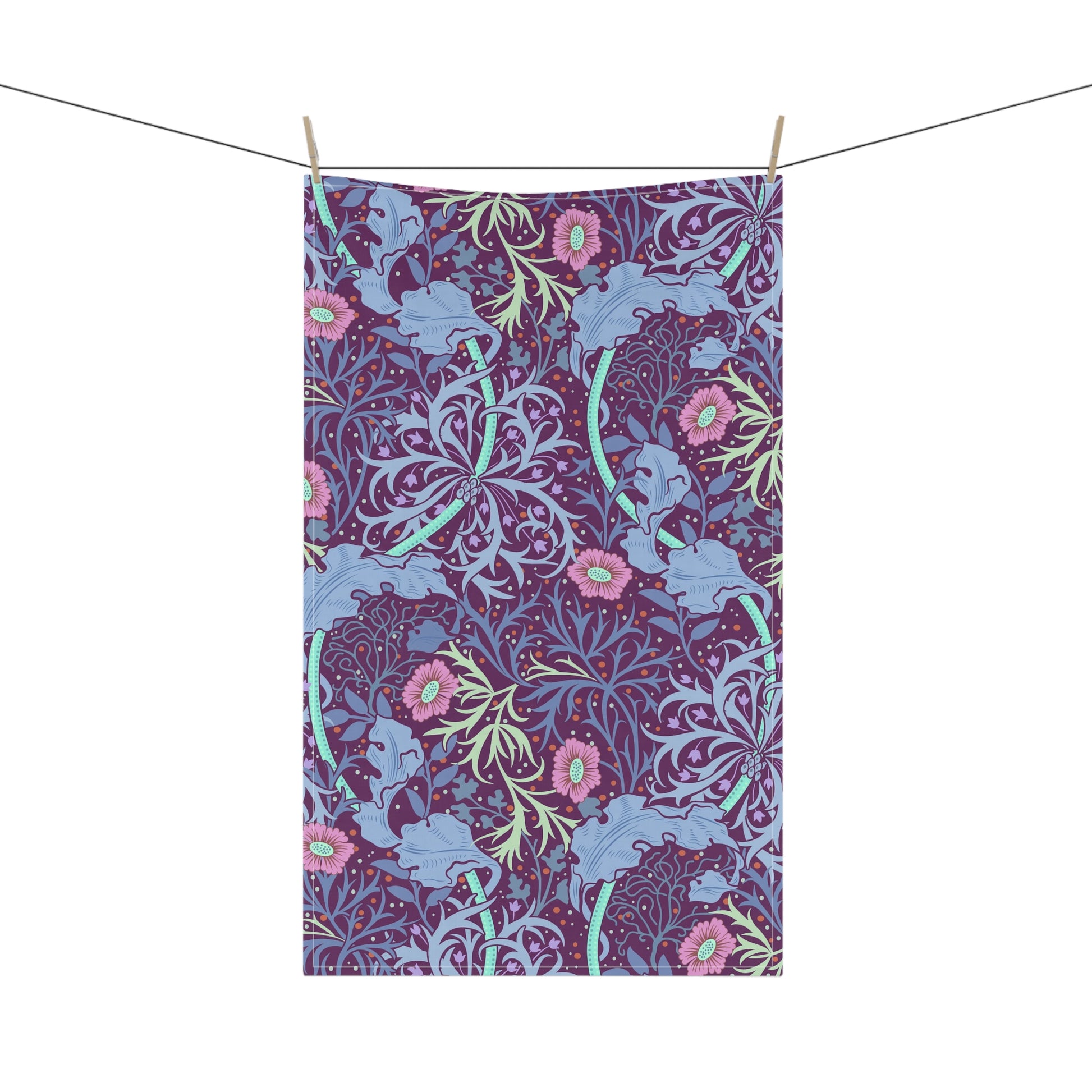A kitchen tea towel featuring a repeating pattern of seaweed and pink flowers on a purple background.
