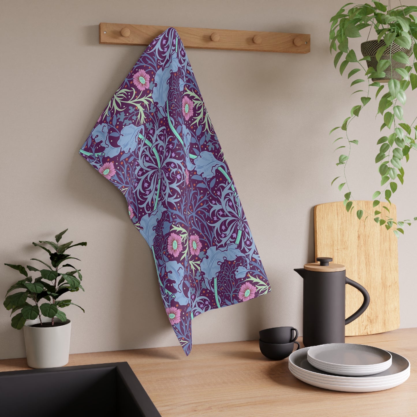 A kitchen tea towel featuring a repeating pattern of seaweed and pink flowers on a purple background.