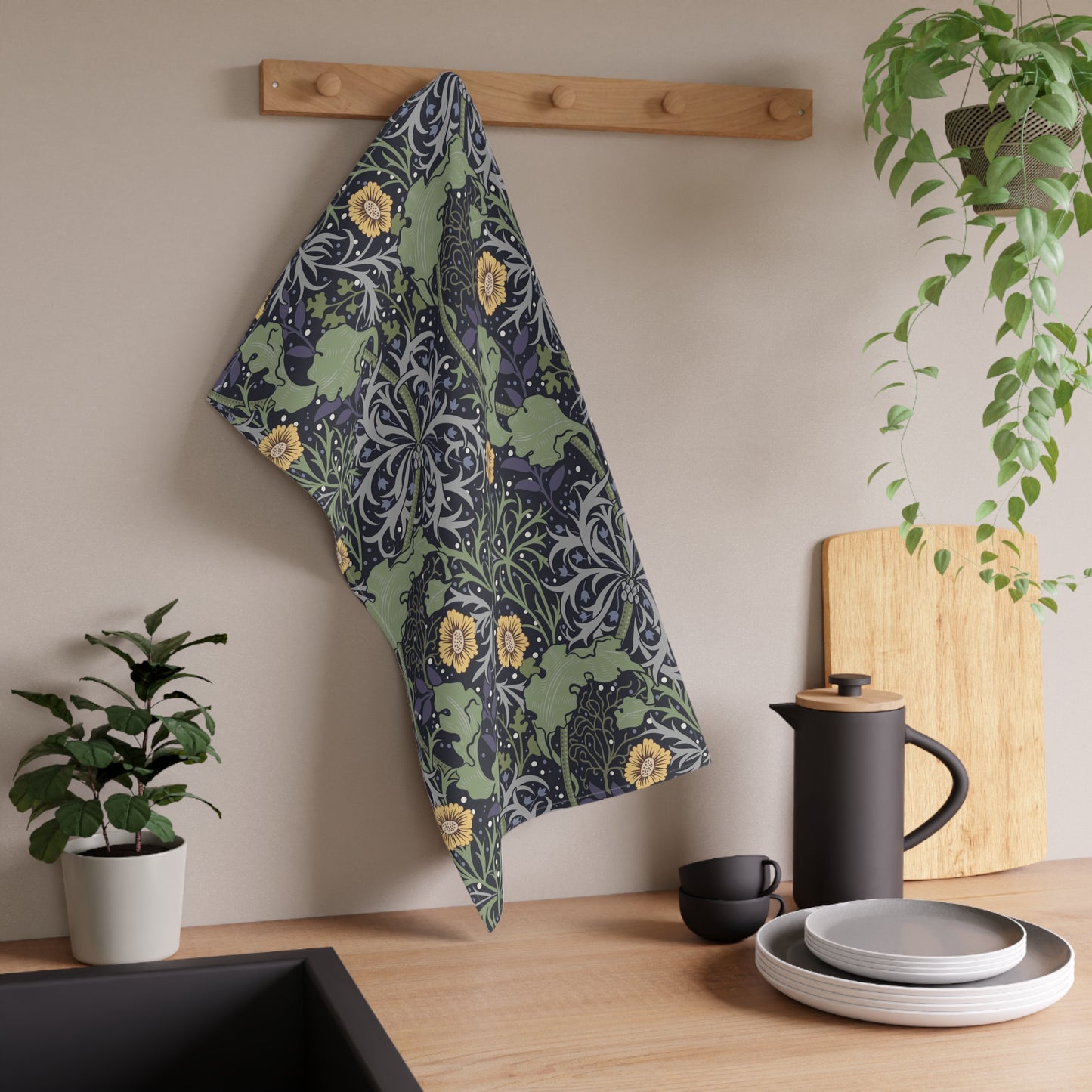 A rectangular kitchen tea towel featuring a repeating pattern of seaweed and yellow flowers on a green background.