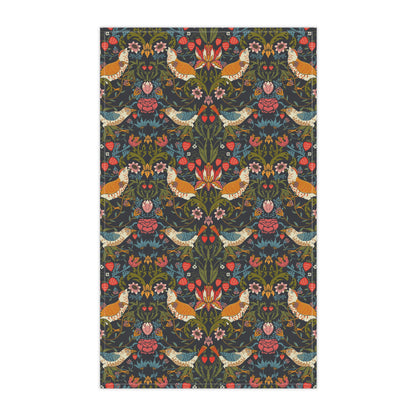 A kitchen tea towel with a repeating pattern featuring birds, flowers, and leaves in dark background, inspired by William Morris' Strawberry Thief design.