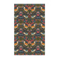 A kitchen tea towel with a repeating pattern featuring birds, flowers, and leaves in dark background, inspired by William Morris' Strawberry Thief design.