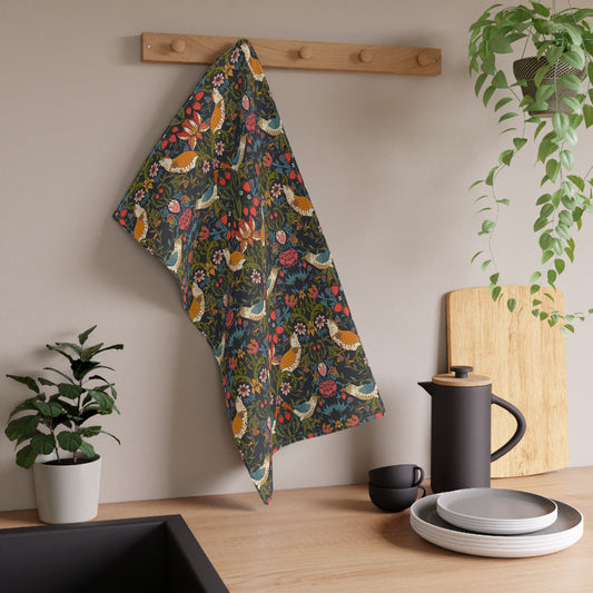A kitchen tea towel with a repeating pattern featuring birds, flowers, and leaves in dark background, inspired by William Morris' Strawberry Thief design.
