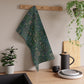 A kitchen tea towel with a green and violet floral pattern inspired by William Morris - Violet and Columbine Collection.