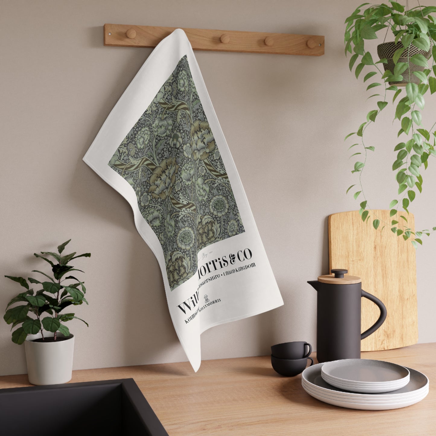 Tea towel with green pattern and text hanging on a wooden rack in a kitchen setting.