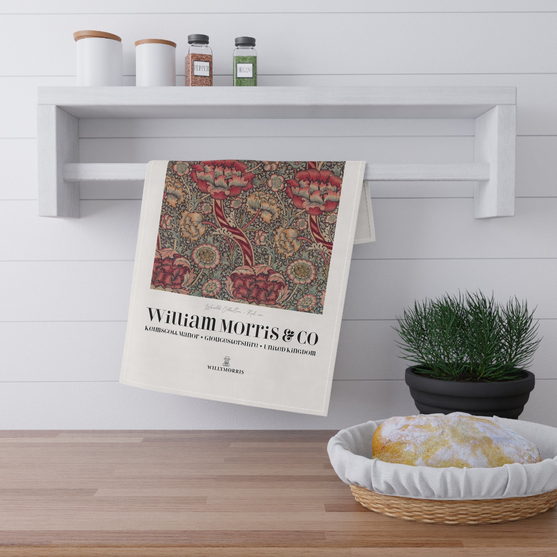 Decorative towel with floral pattern and 'William Morris & Co' text hanging on a shelf in a kitchen.