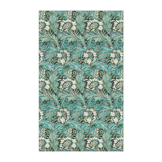 A kitchen tea towel with a floral pattern inspired by William Morris, in shades of blue, green, and white.