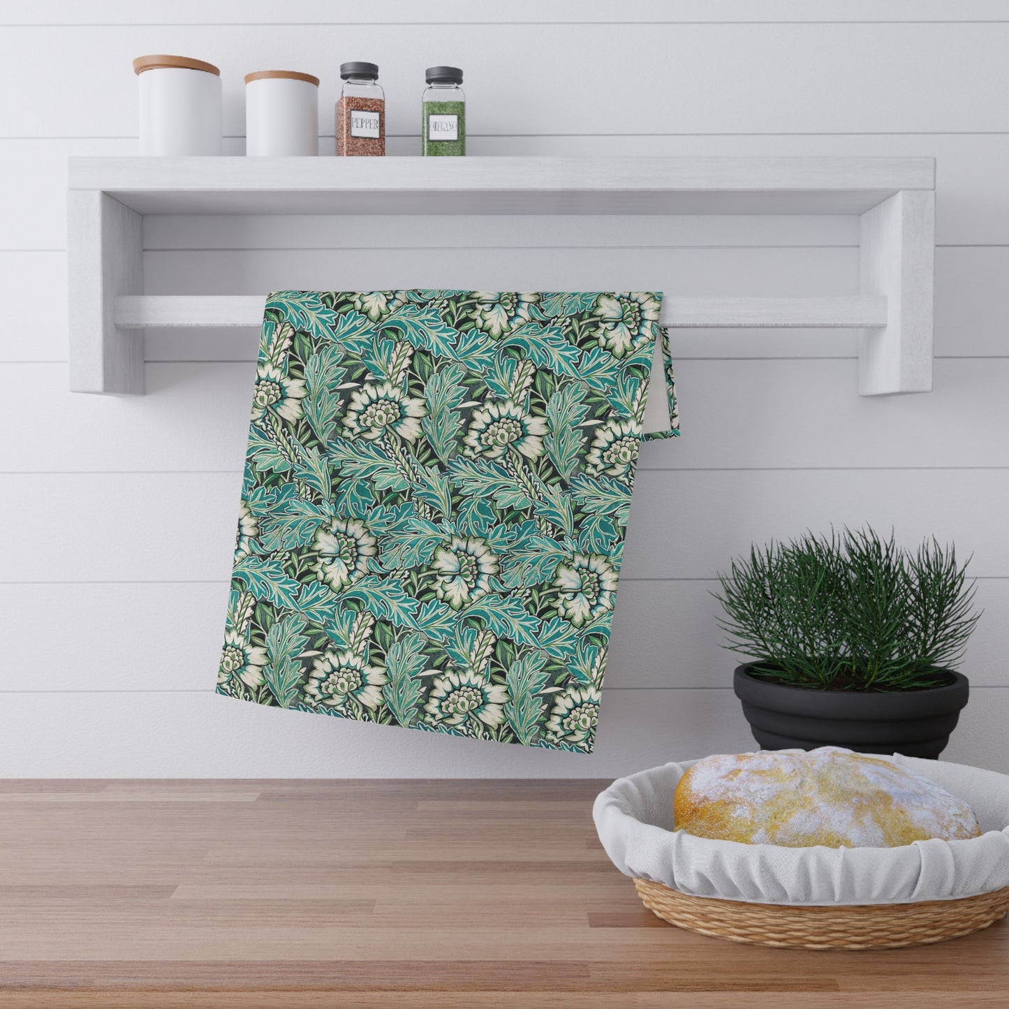 A kitchen tea towel with a floral pattern inspired by William Morris, in shades of blue, green, and white.