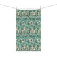 A kitchen tea towel with a floral pattern inspired by William Morris, in shades of blue, green, and white.
