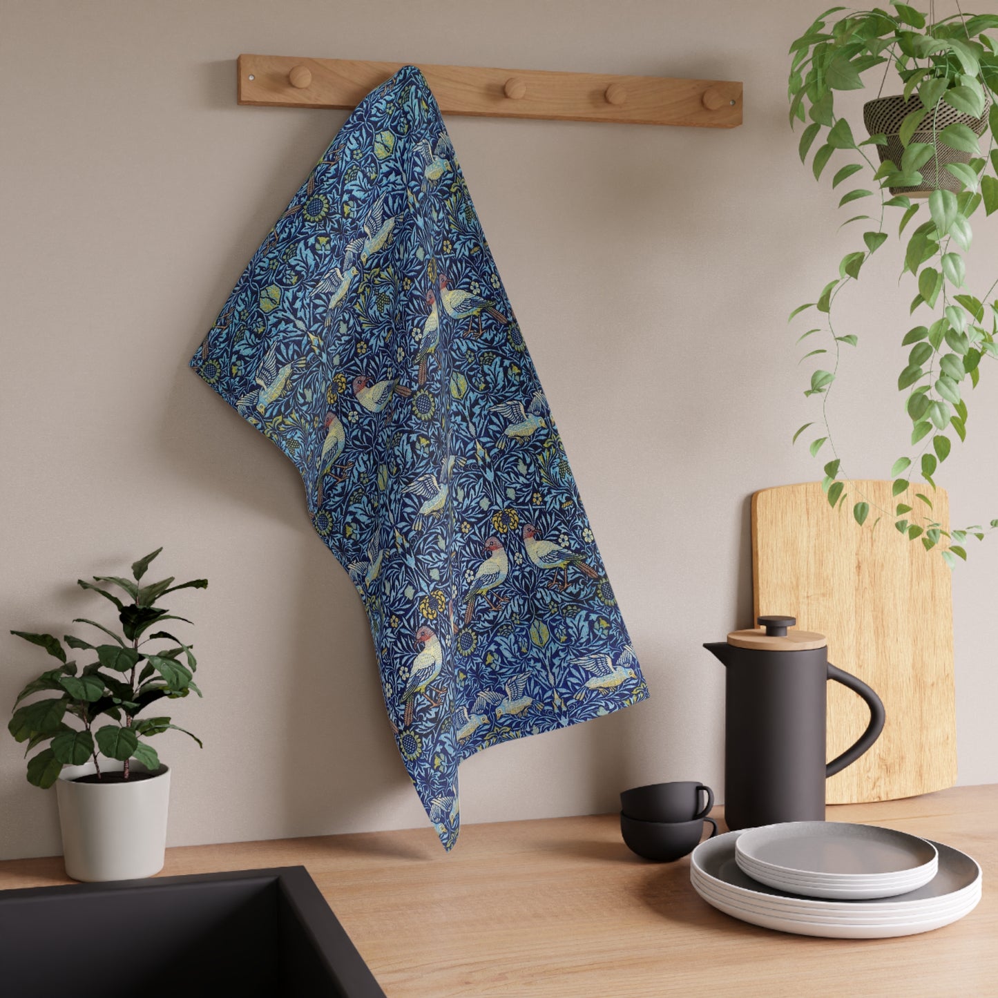 Blue floral towel hanging on a wooden rack above a kitchen counter with plates, cups, and a plant.