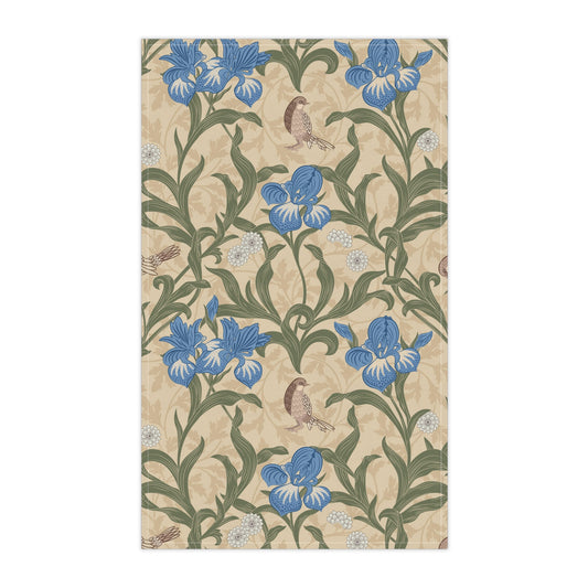 A kitchen tea towel with a William Morris & Co floral pattern featuring blue irises, birds, and a beige background.