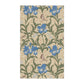 A kitchen tea towel with a William Morris & Co floral pattern featuring blue irises, birds, and a beige background.
