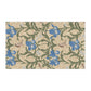 A kitchen tea towel with a William Morris & Co floral pattern featuring blue irises, birds, and a beige background.