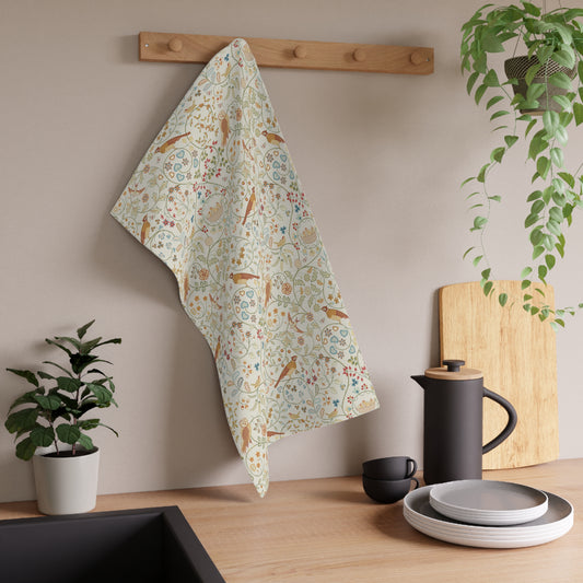 Floral patterned towel hanging on a wooden rack with kitchen items and plants in the background.