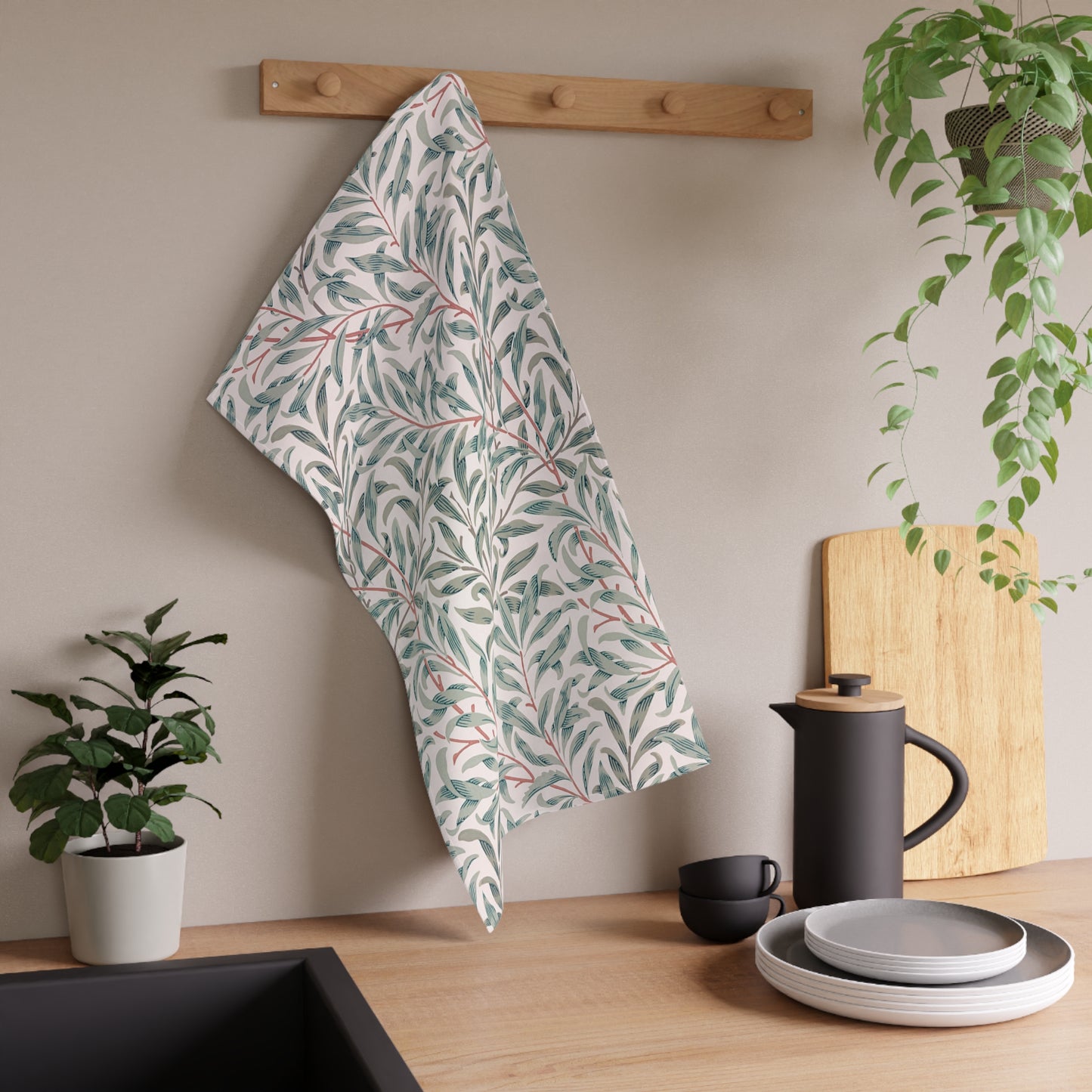 Kitchen setting with a leaf-patterned towel hanging, plants, and kitchenware.
