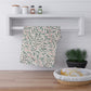 Striped towel hanging on a wooden shelf with a plant and basket in the foreground.