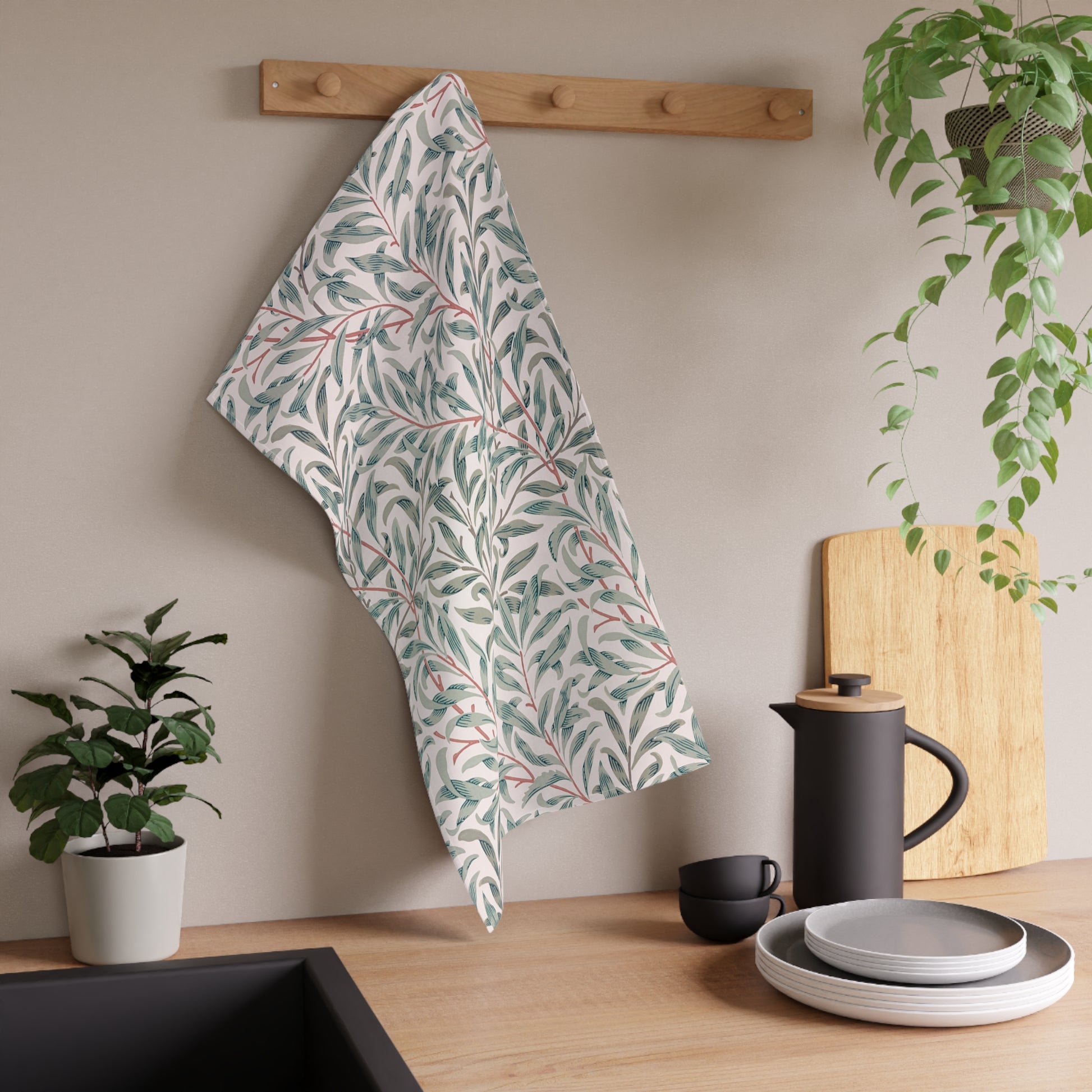 Kitchen setting with a leaf-patterned towel hanging, plants, and kitchenware.