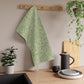 A green kitchen tea towel with a floral and leaf pattern inspired by William Morris & Co - Acorn and Oak Leaves Collection.