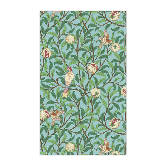 A kitchen tea towel with a blue background featuring bird and pomegranate patterns inspired by William Morris.