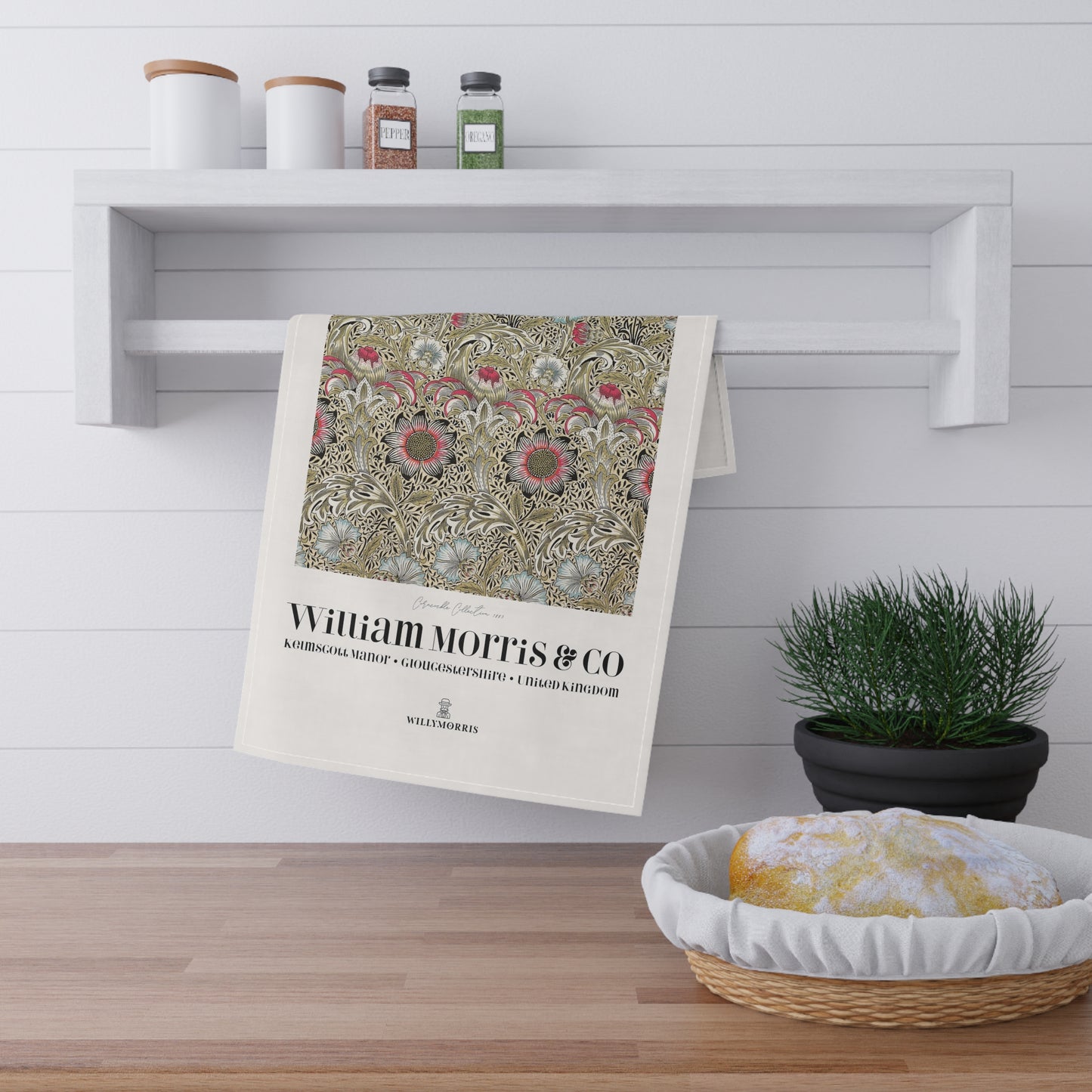 Decorative towel with floral pattern and 'William Morris & Co' text hanging on a shelf with kitchen items.