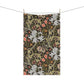 A rectangular tea towel with a dense botanical and floral pattern hangs from two clips on a string against a plain white background.