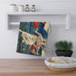 A kitchen tea towel featuring a vibrant, William Morris & Co artistic design with a figure in red and another in white, set against a blue background with greenery.