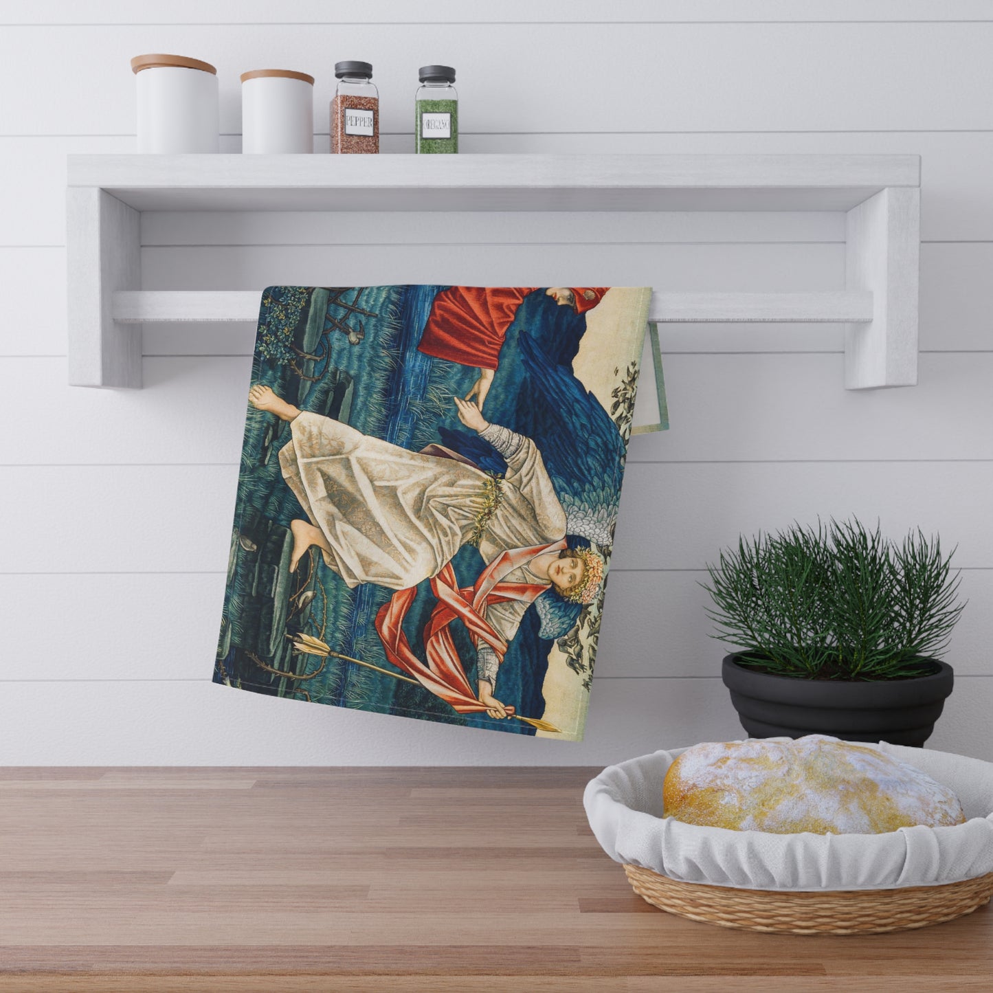 A kitchen tea towel featuring a vibrant, William Morris & Co artistic design with a figure in red and another in white, set against a blue background with greenery.