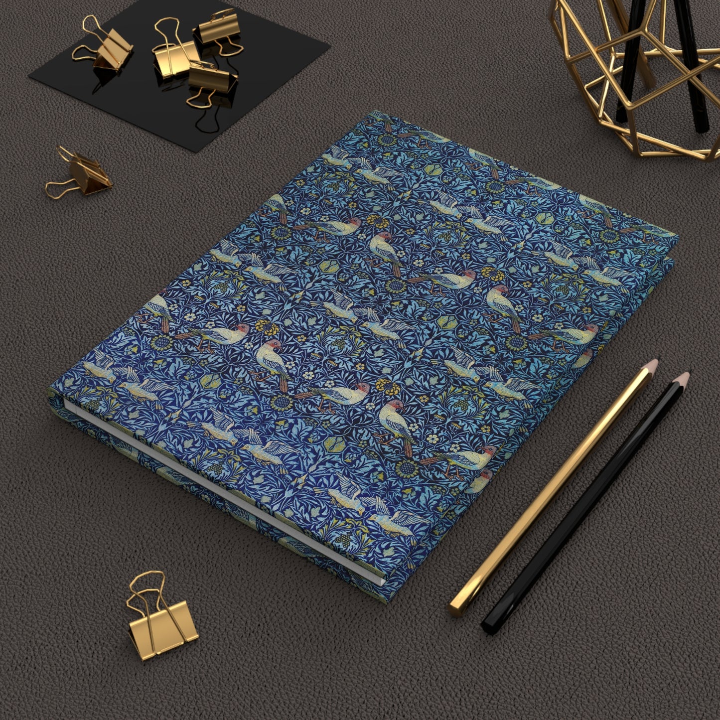 Blue notebook with bird pattern on a dark surface with office supplies