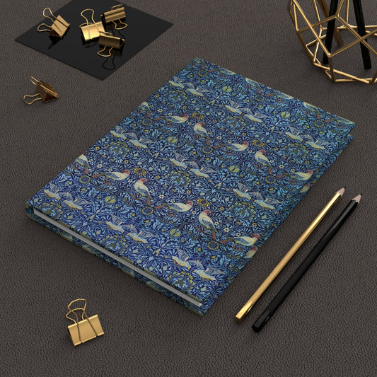 Blue notebook with bird pattern on a dark surface with office supplies