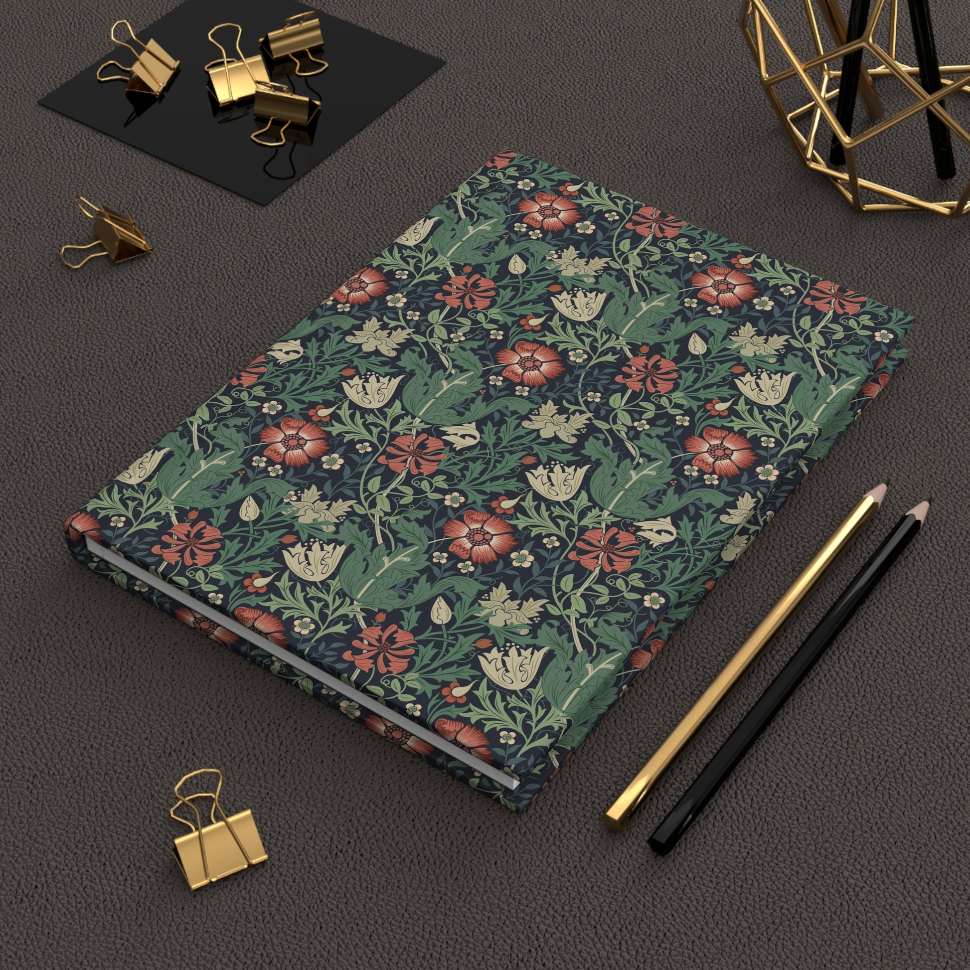 Floral William Morris & Co patterned notebook on a dark surface with office supplies.