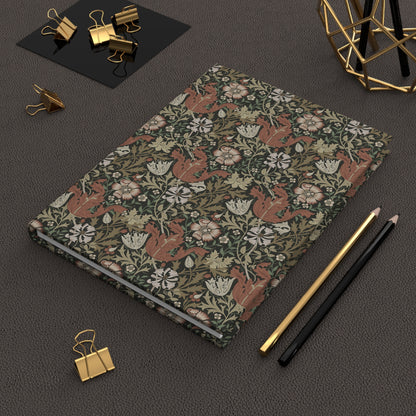 Notebook with William Morris & Co floral and fox pattern on a dark surface with office supplies.